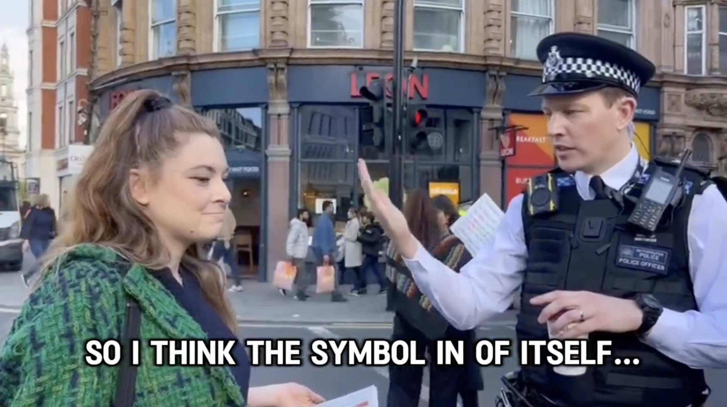 A distressed Jewish woman is seen complaining about the Nazi symbol on placards